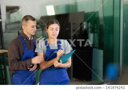 Two glass workshop workers discussing documents Two glass workshop workers discussing documents 141974241