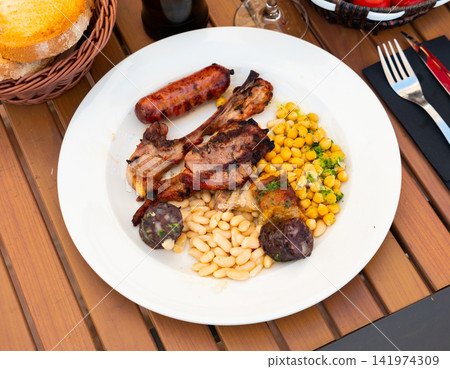 Lamb ribs on bone, sausage, piece of black pudding are complemented with stewed beans Lamb ribs on bone, sausage, piece of black pudding are complemented with stewed beans 141974309