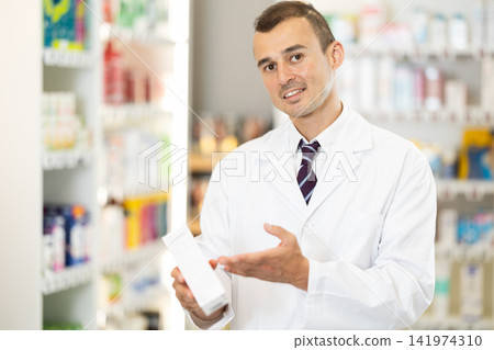 Male consultant pharmacist holds box in hands and offers to purchase remedy to alleviate condition Male consultant pharmacist holds box in hands and offers to purchase remedy to alleviate condition 141974310
