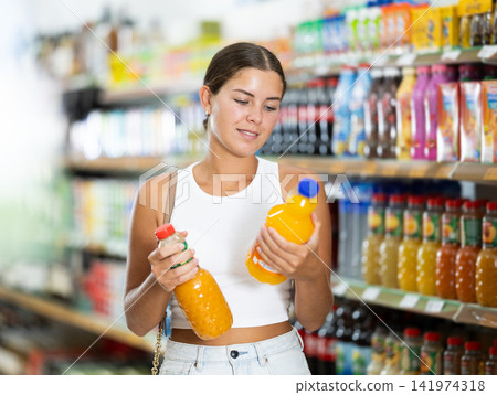 Girl in supermarket buys bottle of soda drink Girl in supermarket buys bottle of soda drink 141974318