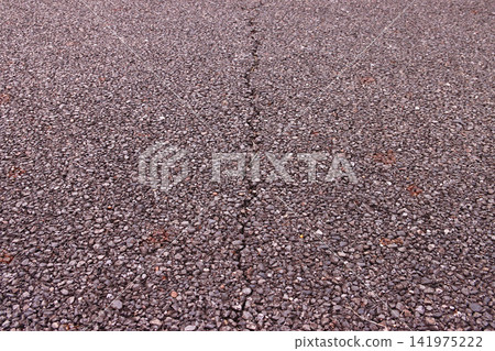 An asphalt road with a single crack running down the middle due to age-related deterioration. An asphalt road with a single crack running down the middle due to age-related deterioration. 141975222