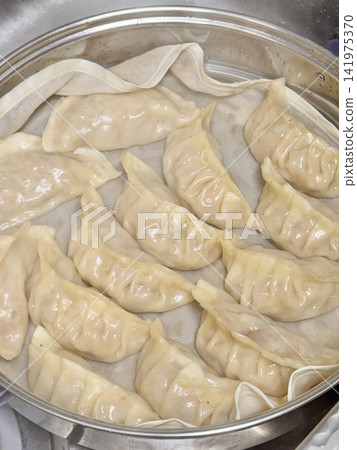 Steamed or fried mandu dumplings served alongside fermented kimchi, creating a classic Korean pairing that combines savory, tender dumplings with spicy, tangy, and flavorful fermented vegetables Steamed or fried mandu dumplings served alongside fermented kimchi, creating a classic Korean pairing that combines savory, tender dumplings with spicy, tangy, and flavorful fermented vegetables 141975370