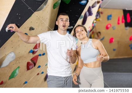 Young girl and man discussing cliimbing routes near bouldering wall Young girl and man discussing cliimbing routes near bouldering wall 141975550