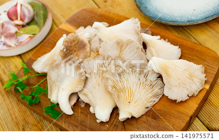 Preparing to cook soup or other dishes from fresh oyster mushrooms in kitchen Preparing to cook soup or other dishes from fresh oyster mushrooms in kitchen 141975571