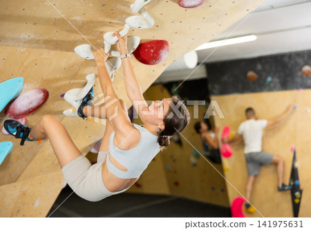 Young woman practicing rock climbing on climbing wall Young woman practicing rock climbing on climbing wall 141975631