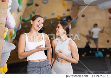Girls chatting casually during break between climbs in bouldering gym Girls chatting casually during break between climbs in bouldering gym 141975664