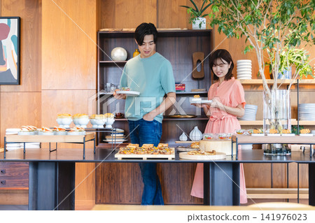 一對年輕夫婦在飯店自助餐廳挑選食物。 141976023