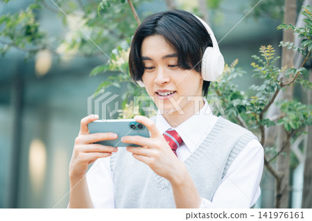 Student: A male student looking at his smartphone. Photo cooperation: Denpa Gakuen Tokyo Electronics College. 141976161