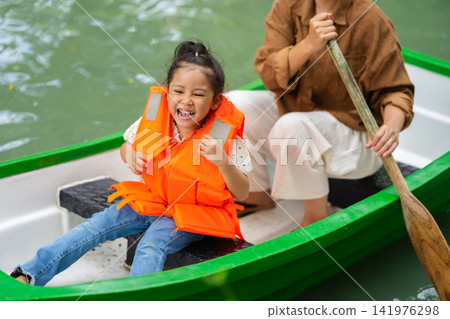 close-up of smiling preschool child girl in a life jacket aboard a rowboat. 141976298