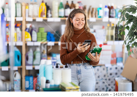 Young woman scanning QR-code on dishwashing liquid in supermarket Young woman scanning QR-code on dishwashing liquid in supermarket 141976495