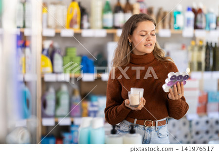 Young woman choosing scented candles in household store Young woman choosing scented candles in household store 141976517