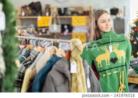 Teenage girl chooses sweater in clothing store 141976518