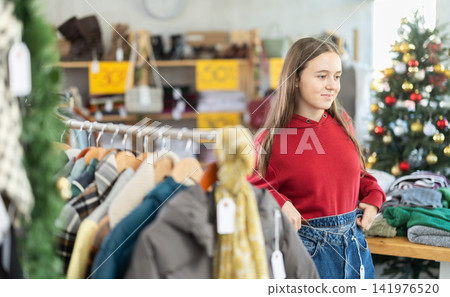 Teenage girl chooses jeans trousers in clothing store 141976520