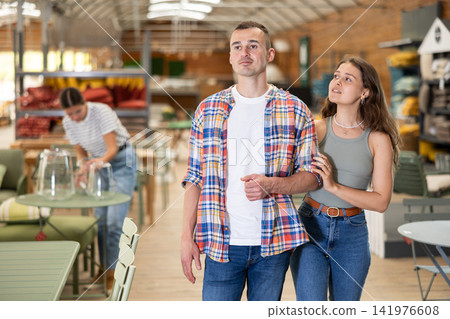 Spouses look for something in furniture store, searching for perfect item to complete patio Spouses look for something in furniture store, searching for perfect item to complete patio 141976608