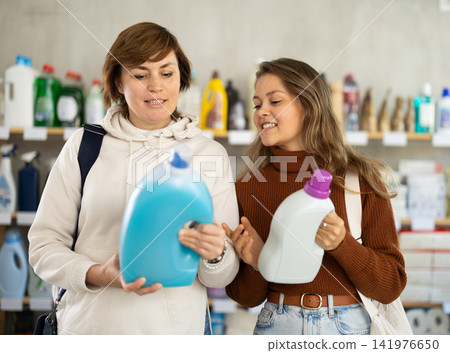 Mum with adult daughter purchases household chemicals in store, choose liquid detergent Mum with adult daughter purchases household chemicals in store, choose liquid detergent 141976650