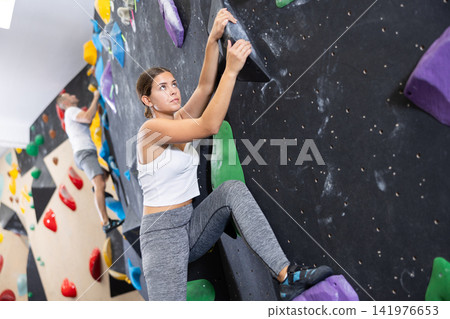 Young woman practicing rock climbing on climbing wall Young woman practicing rock climbing on climbing wall 141976653