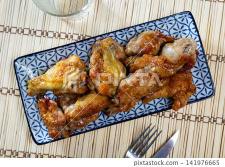 Service plate containing delicious fried chicken wings with necessary table laying closeup Service plate containing delicious fried chicken wings with necessary table laying closeup 141976665