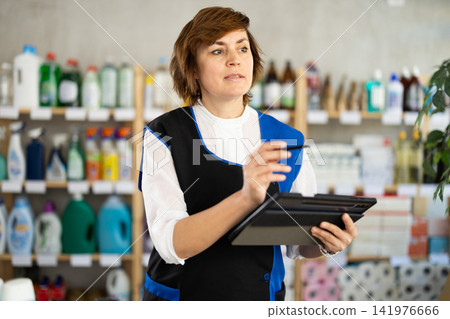 Woman seller, with tablet in hands, make inventory in store. Woman seller, with tablet in hands, make inventory in store. 141976666