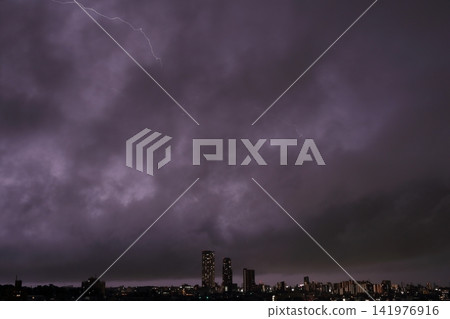 雷雨天氣中雲層內的放電；閃電照亮了城市的夜景。 141976916