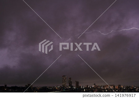 雷雨天氣中雲層內的放電;閃電照亮了城市的夜景。 雷雨天氣中雲層內的放電;閃電照亮了城市的夜景。 141976917