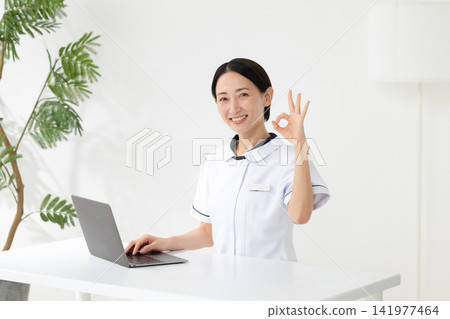 A woman in white coat playing an okay sign A woman in white coat playing an okay sign 141977464