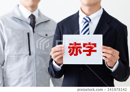 A young businessman in a suit holding a whiteboard with red ink, and a middle-aged man in work clothes. A young businessman in a suit holding a whiteboard with red ink, and a middle-aged man in work clothes. 141978142