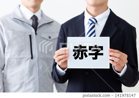 一位身穿西裝、手持紅墨水白板的年輕商人,以及一位身穿工作服的中年男子。 一位身穿西裝、手持紅墨水白板的年輕商人,以及一位身穿工作服的中年男子。 141978147