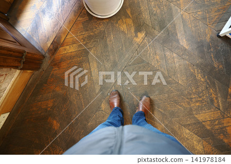 Person standing on wooden floor in a room Person standing on wooden floor in a room 141978184