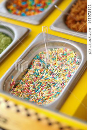 Colorful sprinkles in metal trays at a dessert shop Colorful sprinkles in metal trays at a dessert shop 141978191