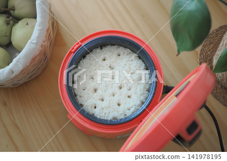 Cooked rice in a rice cooker on a wooden table Cooked rice in a rice cooker on a wooden table 141978195