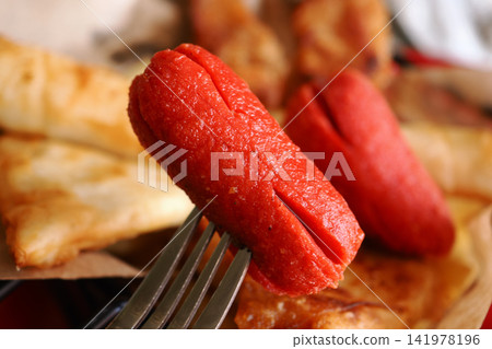 Hot dogs on a fork with side dishes on a plate Hot dogs on a fork with side dishes on a plate 141978196