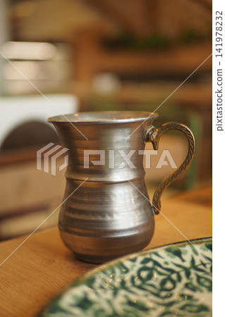 Metal jug of ayran, a turkish drink on wooden table. Metal jug of ayran, a turkish drink on wooden table. 141978232