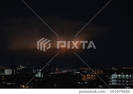Sudden thunderstorm: Developed cumulonimbus clouds illuminated by lightning, and the city's night view. Sudden thunderstorm: Developed cumulonimbus clouds illuminated by lightning, and the city's night view. 141979084