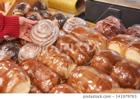 Hand Selecting Glazed Cinnamon Roll From Packaged Bakery Assortment On Supermarket Shelf Hand Selecting Glazed Cinnamon Roll From Packaged Bakery Assortment On Supermarket Shelf 141979763