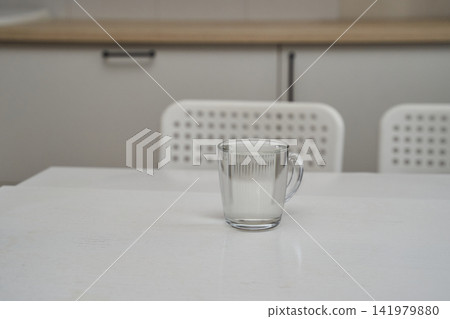 Glass Of Milk Placed On White Table In Minimalist Kitchen Dining Area With Perforated Chairs Glass Of Milk Placed On White Table In Minimalist Kitchen Dining Area With Perforated Chairs 141979880