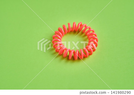 Neon Spiral Hair Tie Lying Flat On Seamless Green Backdrop Studio Surface Showing Coiled Plastic Neon Spiral Hair Tie Lying Flat On Seamless Green Backdrop Studio Surface Showing Coiled Plastic 141980290