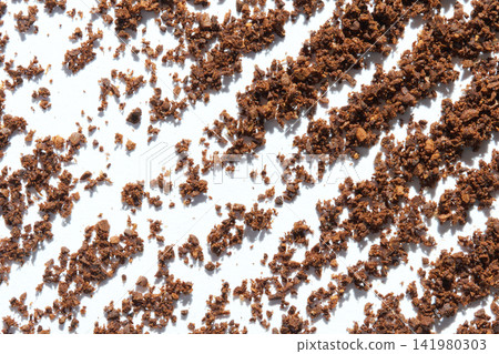 Ground Coffee Granules Scattered In Diagonal Pattern On White Surface Closeup Revealing Texture Ground Coffee Granules Scattered In Diagonal Pattern On White Surface Closeup Revealing Texture 141980303