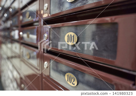 Row Of Numbered Metal Mailboxes Showing 101 And 102 Near Apartment Mailroom Entrance With Brass Row Of Numbered Metal Mailboxes Showing 101 And 102 Near Apartment Mailroom Entrance With Brass 141980323
