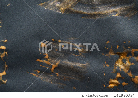 Gold Pigment Streaks And Smudges On Dark Paper Creating Brushed Metallic Texture And Scattered Gold Pigment Streaks And Smudges On Dark Paper Creating Brushed Metallic Texture And Scattered 141980354