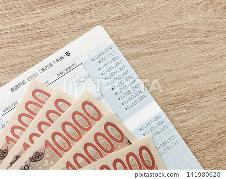 Bankbook and money (wood-grain desk background) Bankbook and money (wood-grain desk background) 141980628
