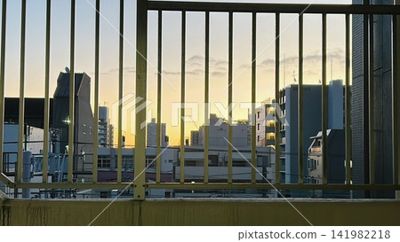 城市的夕陽和剪影越過鐵絲網圍欄,映照出一片壯麗的景象。 城市的夕陽和剪影越過鐵絲網圍欄,映照出一片壯麗的景象。 141982218