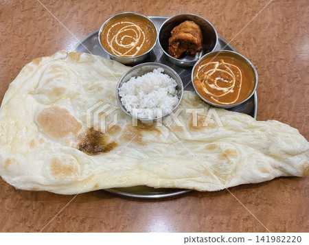 A set of freshly baked large naan bread and two kinds of Indian curry. A set of freshly baked large naan bread and two kinds of Indian curry. 141982220