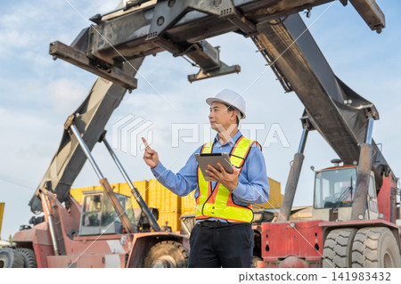 Construction manager directing machinery operations at a job site Construction manager directing machinery operations at a job site 141983432