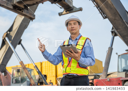 Construction worker using tablet to oversee site operations outdoors. Construction worker using tablet to oversee site operations outdoors. 141983433