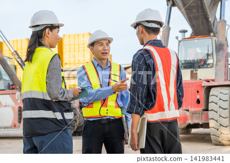 Construction team discussing project details on site for safety compliance. Construction team discussing project details on site for safety compliance. 141983441