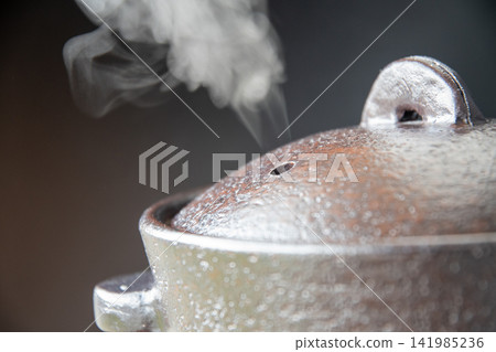 Rice cooked in an earthenware pot that emits steam Rice cooked in an earthenware pot that emits steam 141985236