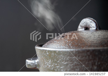 Rice cooked in an earthenware pot that emits steam Rice cooked in an earthenware pot that emits steam 141985237
