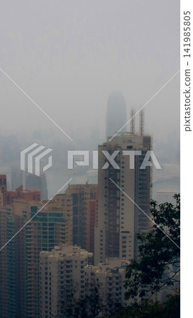 A foggy cityscape view with skyscrapers blending into the misty atmosphere in downtown Hong Kong A foggy cityscape view with skyscrapers blending into the misty atmosphere in downtown Hong Kong 141985805