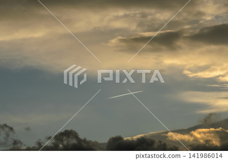 Waves of color paint the evening sky as a plane streaks across the horizon at dusk Waves of color paint the evening sky as a plane streaks across the horizon at dusk 141986014