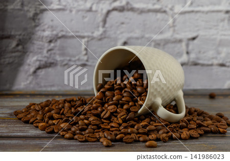 Spilled coffee beans create a warm and inviting atmosphere in a rustic setting 141986023